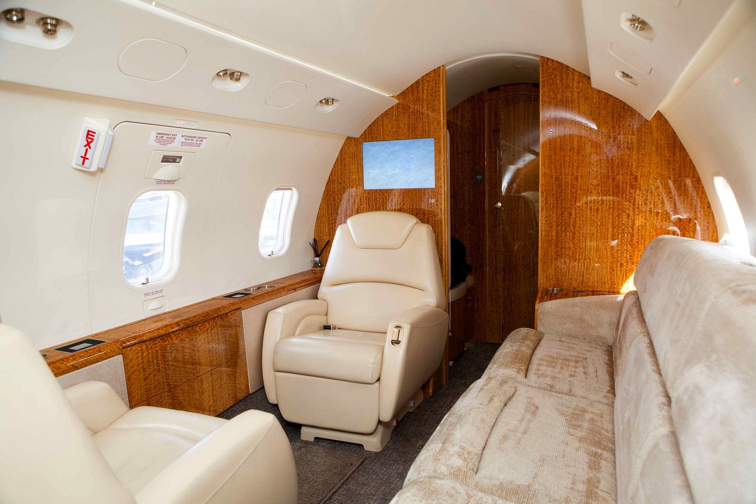 Private jet cabin with cream leather seats and burl-wood paneling