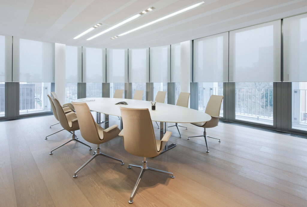 Modern conference room with cream chairs and tailored roller blinds along curved windows
