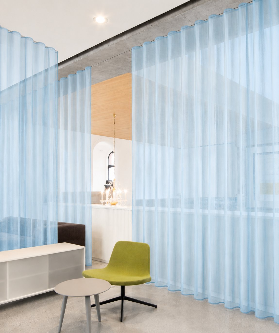 Open-plan workspace with floor-to-ceiling blue acoustic sheer curtains and modern furniture