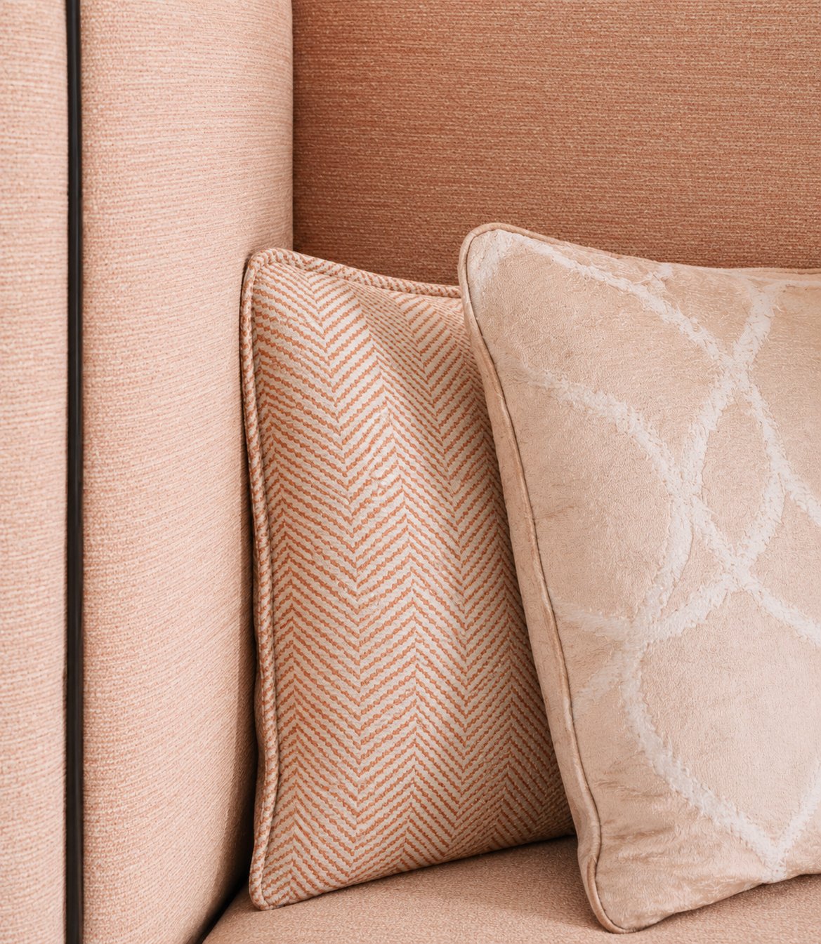 Coral and cream herringbone cushions on a hotel sofa, with damask velvet
