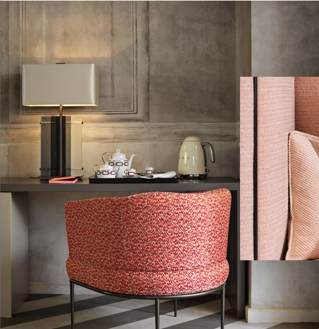 Hotel suite with coral textured armchair, lamp and tea service against grey panelled walls