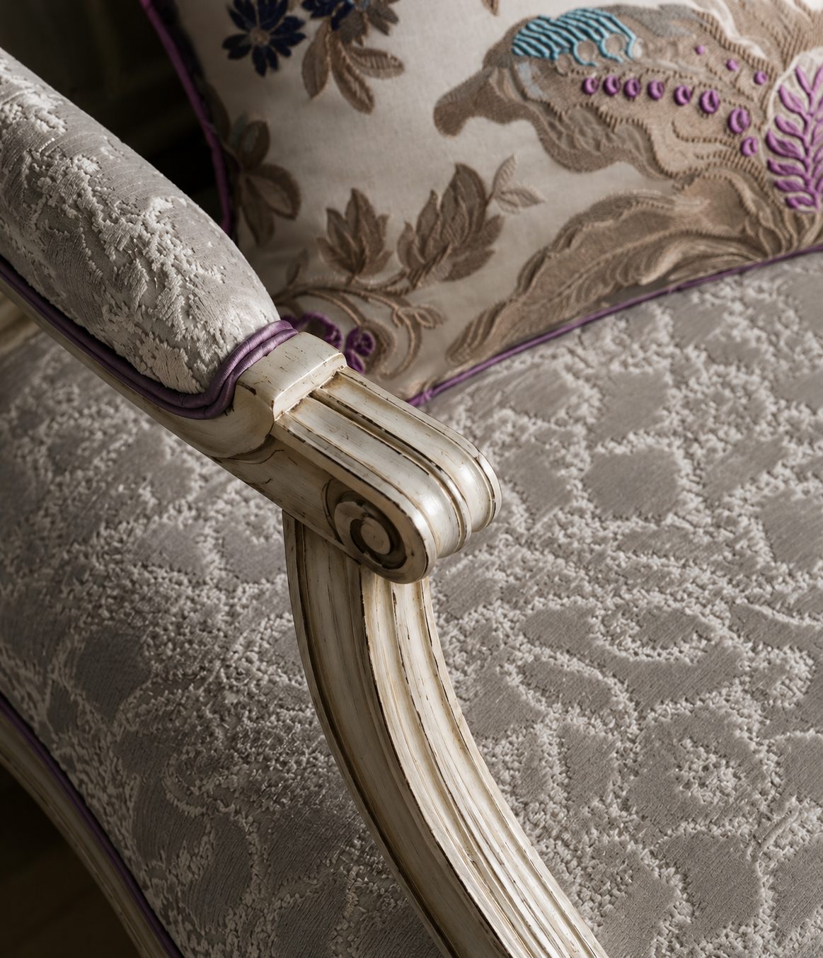Detail of a restored armchair frame in damask with mauve piping