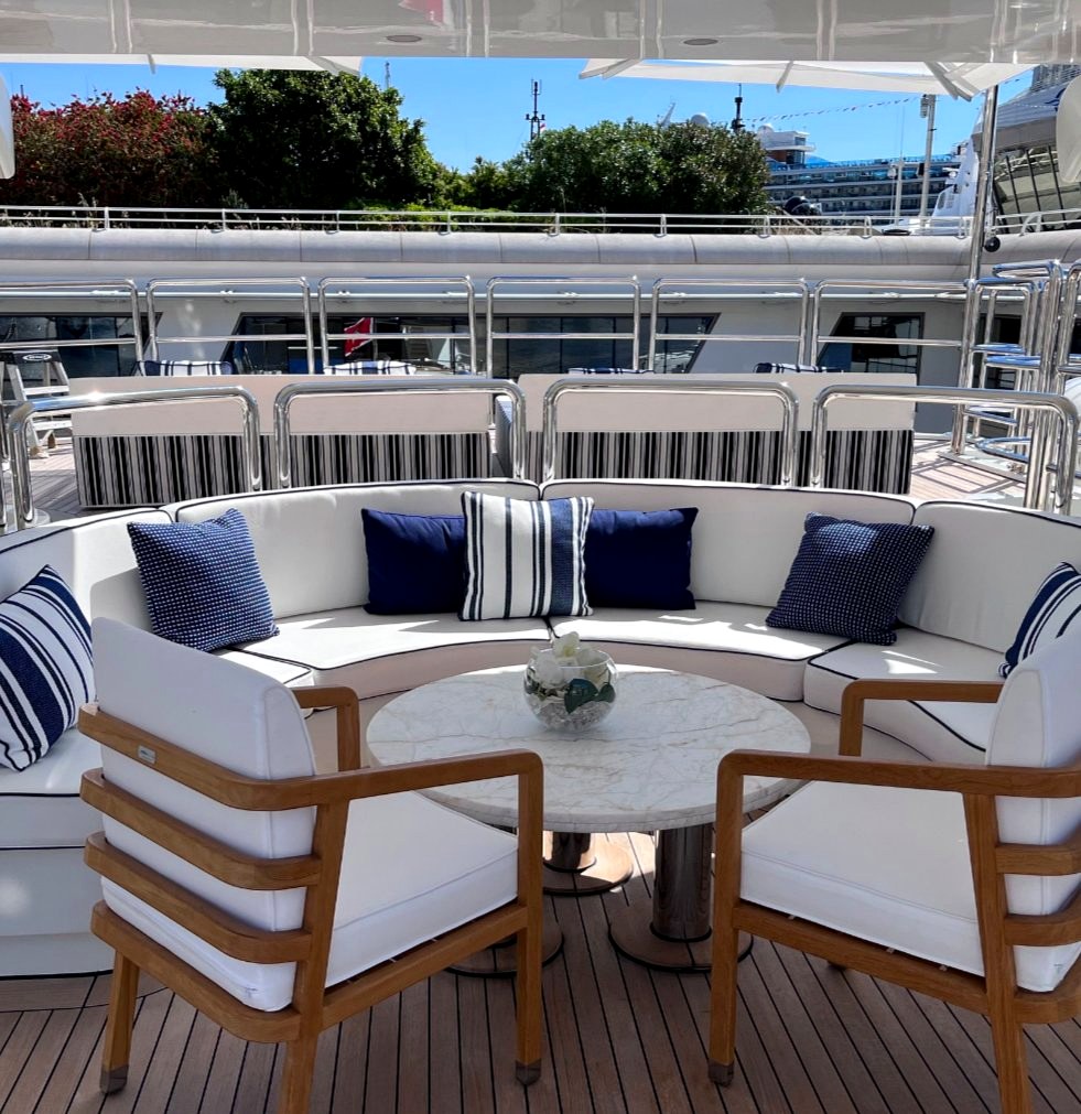 Aft deck of a yacht in Monaco with curved sofa and marine-striped cushions